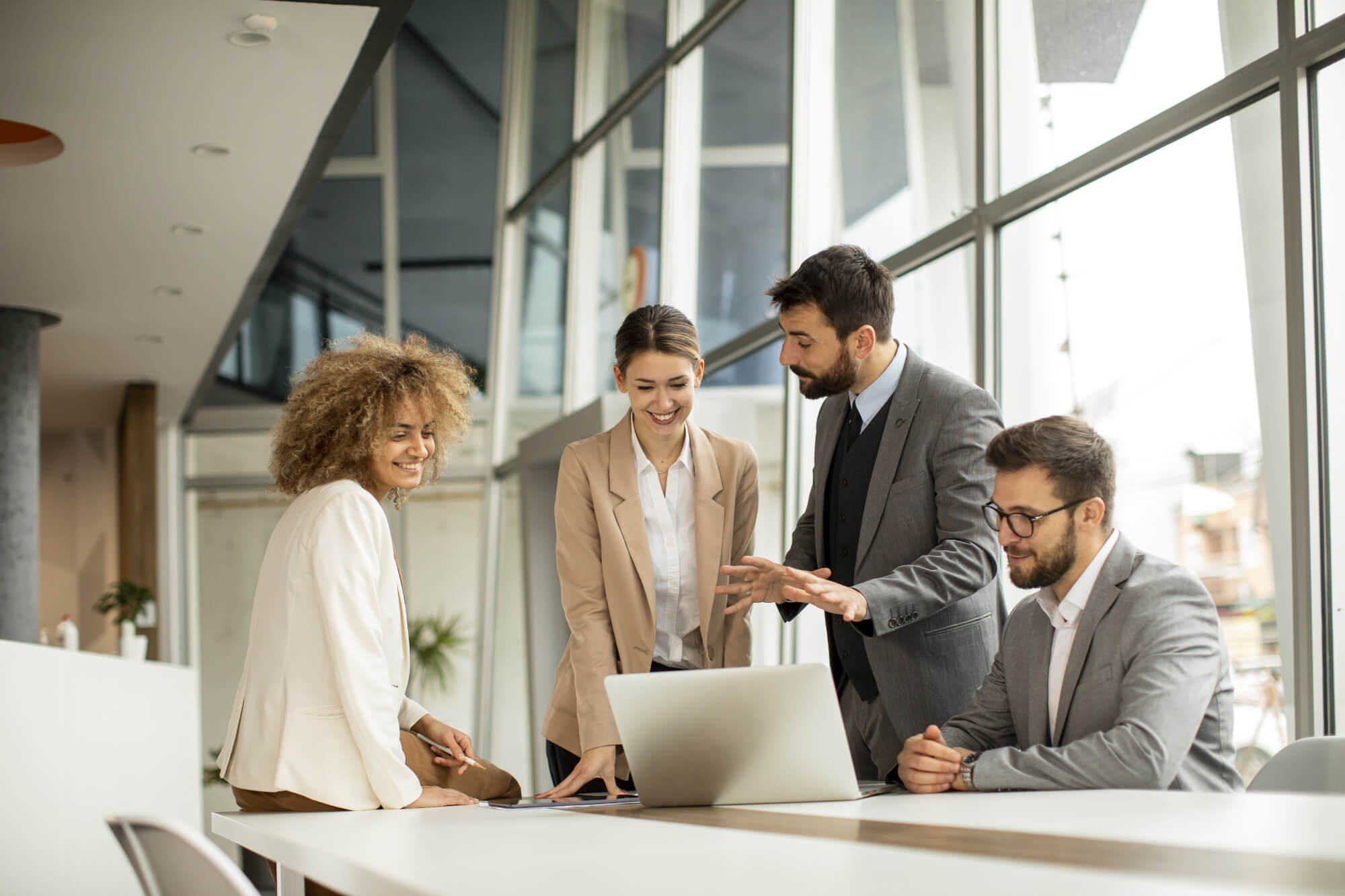 Group of young business professionals gathered around laptop 