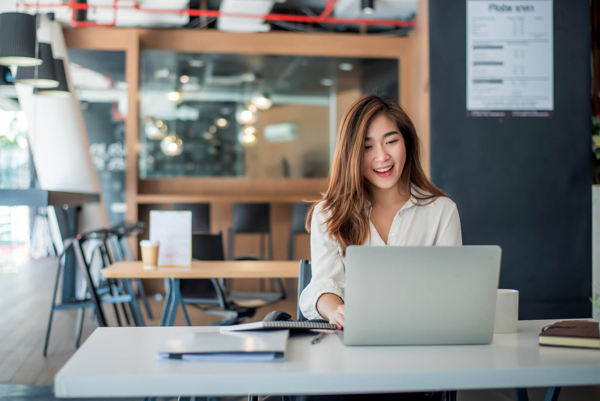 Young professional business woman smiling at laptop in office space 